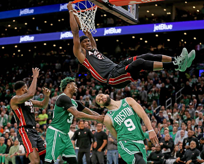 Jimmy Butler holds onto the rim after dunking against the Celtics in the NBA playoffs.